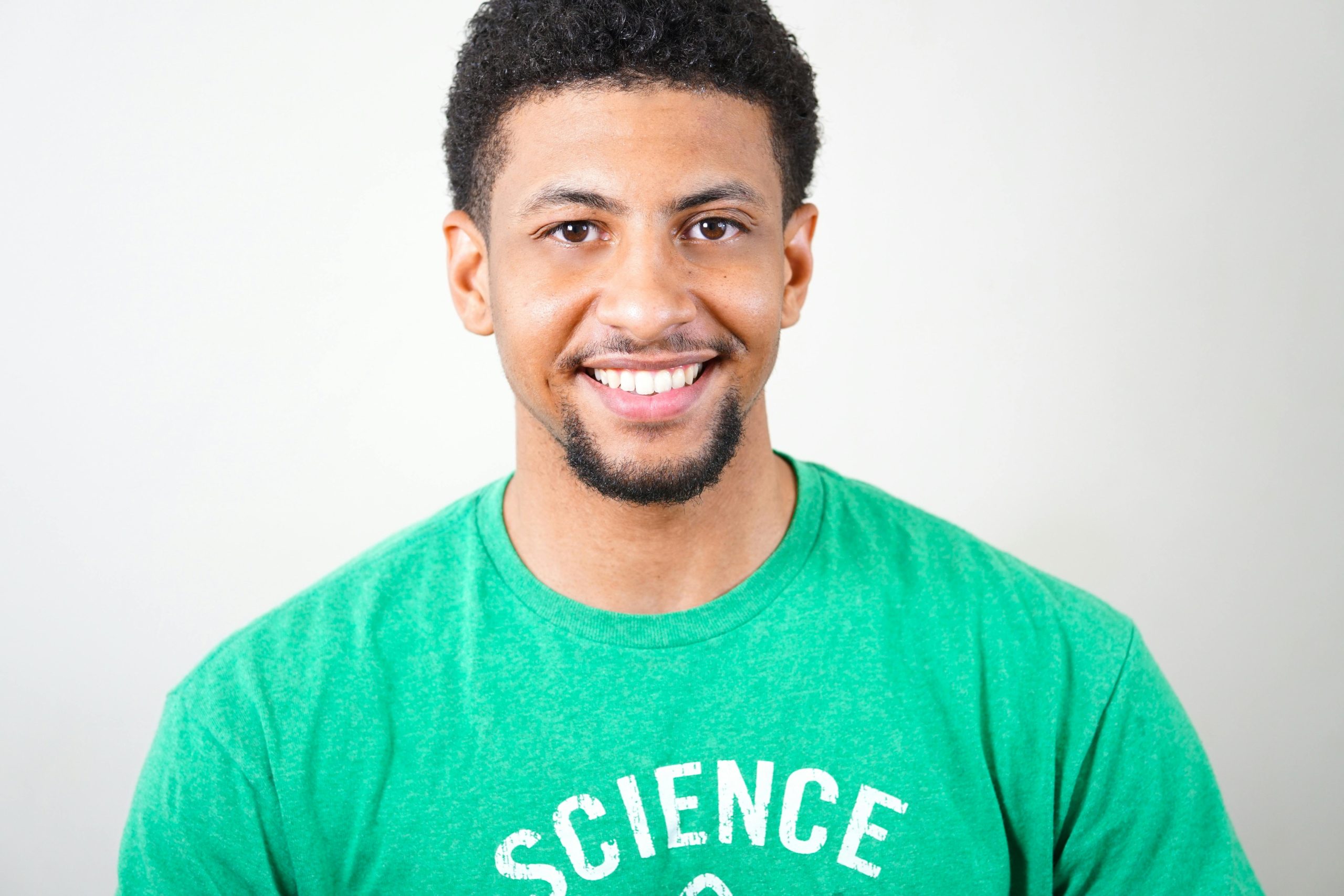 Portrait of a smiling young man wearing a green T-shirt with science text.